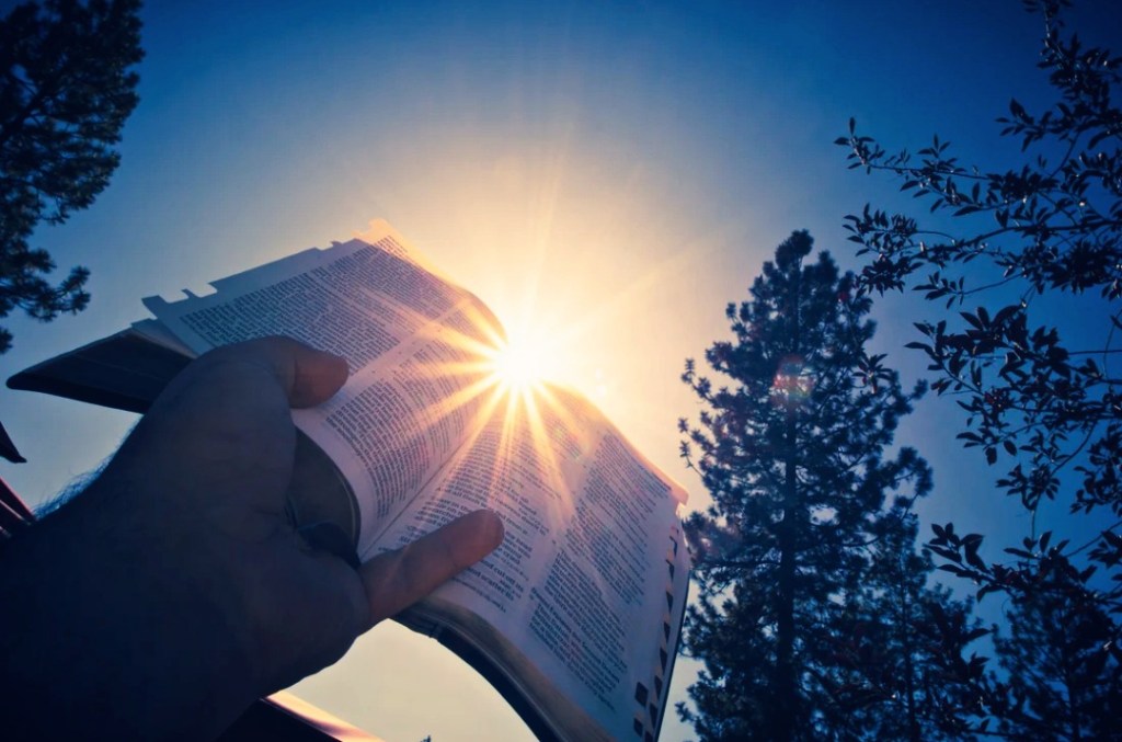 Holding the Bible up to the sky.